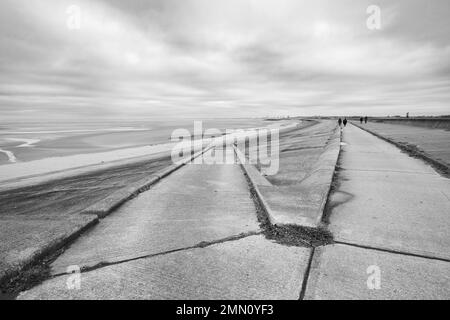 A straight line leads down to the beach at Meols on the Wirral as it splits off from the promenade walk. Stock Photo