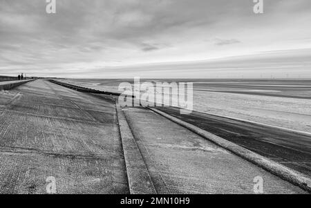 A straight pathway seen leading down to Meols beach on the Wirral captured in black and white in January 2023. Stock Photo
