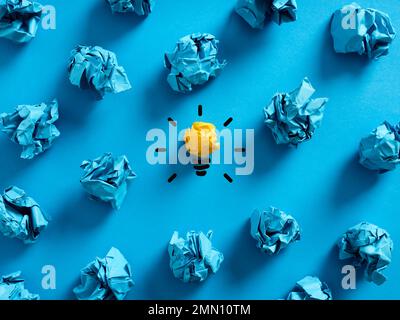 Creativity and idea development. To find a creative idea. Business innovation. Crumpled blue paper balls on blue background with light bulb symbol in Stock Photo