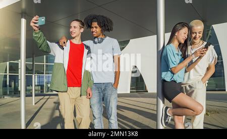 Cheerful group of friends looking smart phone surprised and excited outdoors. Smiling young people. Stock Photo
