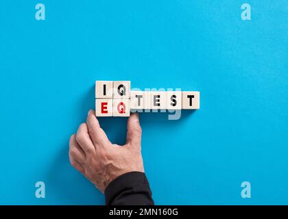 Male hand changes the word IQ test to EQ test on blue background. Choosing Emotional quotient over intelligence quotient. Stock Photo