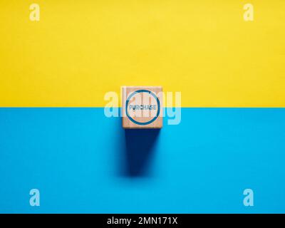 The word Purchase on wooden cube push button on blue and yellow background. Stock Photo