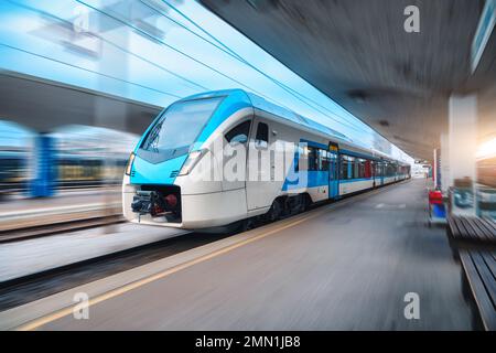 Blue high speed train in motion on the railway station at sunset Stock Photo