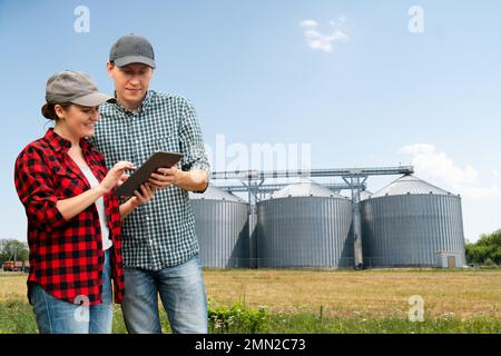 Farmers with digital tablet in front of agricultural silo Stock Photo
