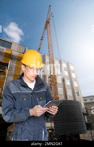 Engineer with a digital tablet on the background of a building under construction Stock Photo