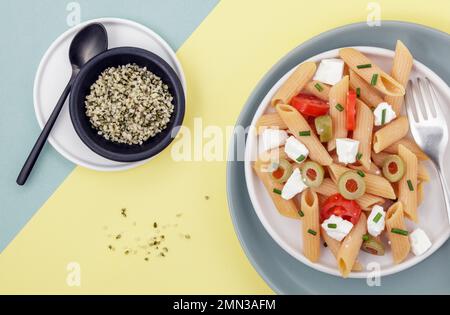 Red lentil penne salad with hempseeds on duo colored background Stock Photo