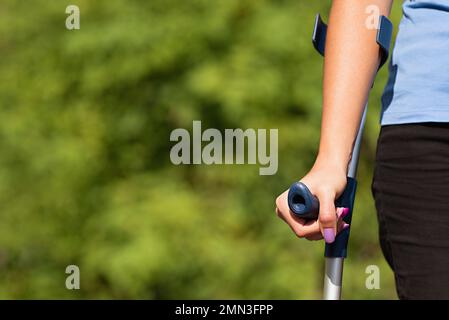 Injured woman trying to walk on crutches in the park Stock Photo