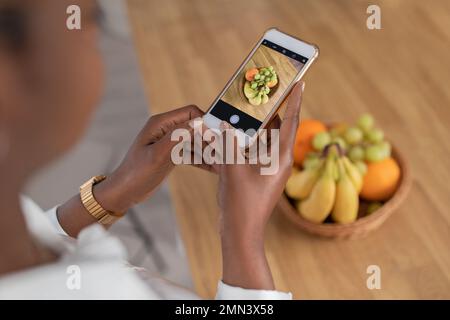 Cropped of black woman taking photo of fruits Stock Photo