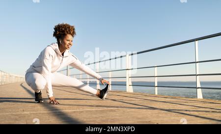 Sporty Black Female Stretching Leg Muscles, Warming Up While Training Outdoors Stock Photo