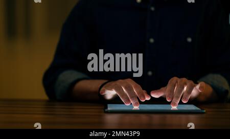 Cropped of man using digital tablet in dark office Stock Photo