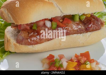 Close up of a choripan, typical argentine sandwich with chorizo and creole sauce. Stock Photo