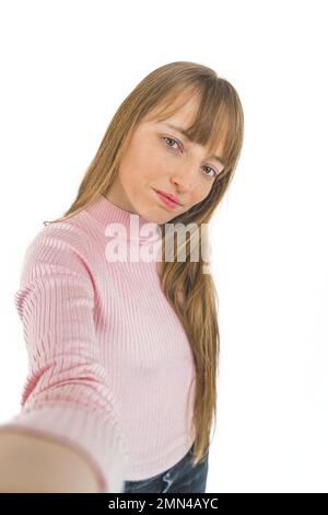 Caucasian woman with long fair hair holding a camera, taking photo of herself on a white background. High quality photo Stock Photo