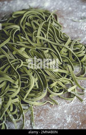 Fresh pasta. Homemade italian raw fettuccine pasta with spinach on wooden table background. High quality photo Stock Photo