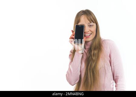Smiling woman with long light hair covering one eye with a smartphone isolated on a white background. High quality photo Stock Photo