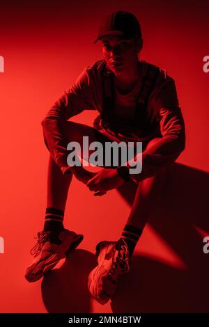 high angle view of african american woman in baseball cap and sweatshirt sitting on red Stock Photo