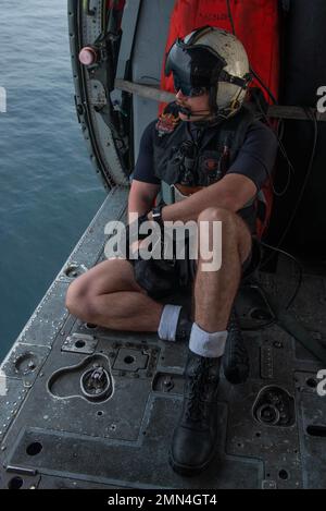 220928-N-LI114-1142 WATERS EAST OF THE KOREAN PENINSULA (Sept. 28, 2022) Naval Air Crewman (Helicopter) 2nd Class Tyler Williamson, from Inola, Oklahoma, looks out of an MH-60S Seahawk helicopter, attached to the Golden Falcons of Helicopter Sea Combat Squadron (HSC) 12, deployed aboard the U.S. Navy’s only forward-deployed aircraft carrier, USS Ronald Reagan (CVN 76), in waters east of the Korean peninsula, Sept. 28. HSC 12, originally established as Helicopter Anti-Submarine Squadron (HS) 2 on March 7, 1952, is the oldest active operational Navy helicopter squadron. The Ronald Reagan Carrier Stock Photo