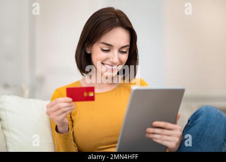 Happy young woman holding digital pad and credit card, closeup Stock Photo