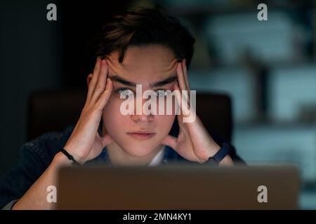Closeup of stressed young man looking at laptop screen Stock Photo