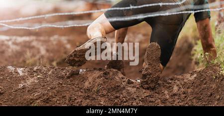 Mud race runners.Crawling,passing under a barbed wire obstacles during extreme obstacle race Stock Photo