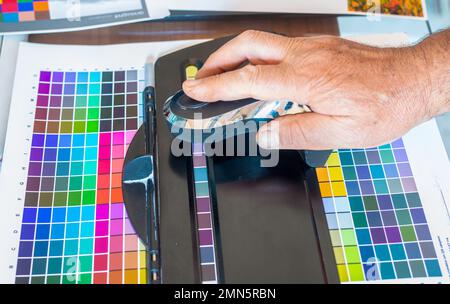 Technician uses a spectrocolorimeter to read patches with various colors for color management related to creating an icc color profile for the printer Stock Photo