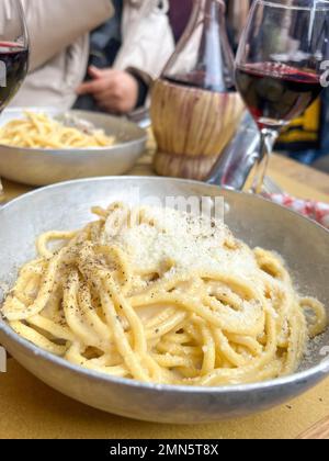 italian food, closeup delicious handmade pasta with cheese on table. typical and traditional Italian spaghetti and local red wine on table in Rome, It Stock Photo