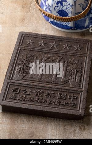 Chinese tea brick from the Hubei Province close up in front of a tea pot on the table Stock Photo