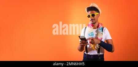 Carnival Brazilian Outfit. Black Man With Carnival Costume Holding Mobile,  Isolated on Orange Background Stock Photo