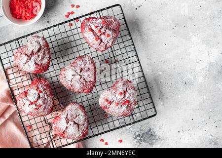 heart shaped red velvet cupcakes with sprinkles on a cooling rack Stock Photo