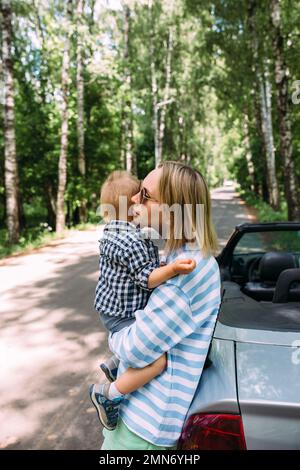 Mom and little son in a convertible car. Summer family road trip to nature Stock Photo