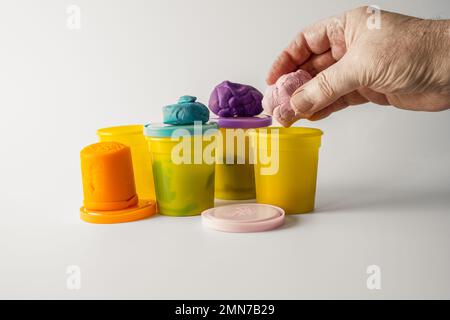 teacher man woman putting away plasticine play dough after use  in school setting for learning Stock Photo