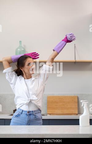 A joyful woman in rubber gloves after home cleaning with a mocap of a pulvilizer with cleaning agent. Cleaning Stock Photo