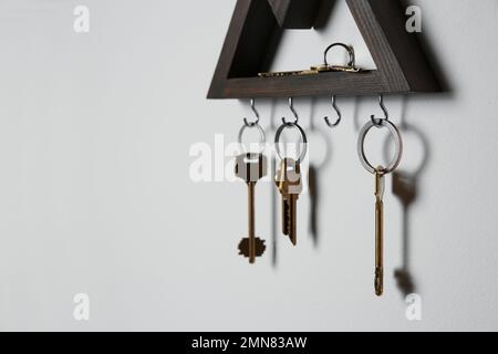 Wooden key holder on light grey wall. Space for text Stock Photo