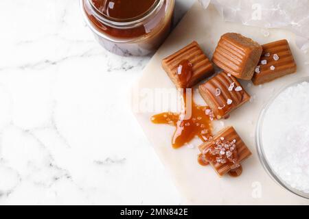 Salted caramel with sauce on marble table, flat lay. Space for text Stock Photo