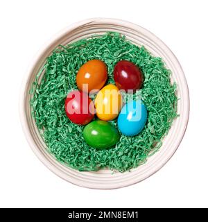 Wood wool nest with Easter eggs in a rattan basket. Colorful dyed Paschal eggs, arranged in a nest of green shredded paper. Stock Photo