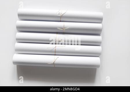 Blank white paper rolls on white background. Mockup paper for magazines, catalogs or newspapers. Printing house theme or wrapping paper for presents. Stock Photo