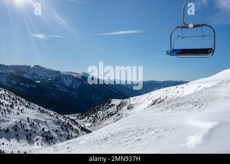 Empty ski lift chair with snowy landscape in the background in the Pyrenees, Andorra. Stock Photo