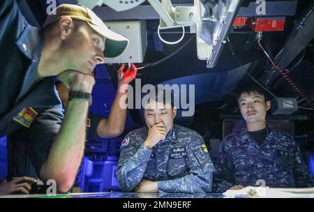 WATERS EAST OF KOREAN PENINSULA (Sept. 30, 2022) Cmdr. Marcus Seeger, left, commanding officer of Arleigh Burke-class guided-missile destroyer USS Benfold (DDG 65), Republic of Korea Navy sailor Lt. Taehyung Kim, center, and Japanese Maritime Self-Defense Force sailor Lt. j. g. Ryou Kato, right, monitor simulated surface contacts during a trilateral anti-submarine warfare exercise in the ship’s combat information center, Sept. 30. Benfold, and Carrier Strike Group (CSG) 5, is conducting a tri-lateral anti-submarine warfare exercise with the JMSDF and ROK Navy. The operations between the Reagan Stock Photo