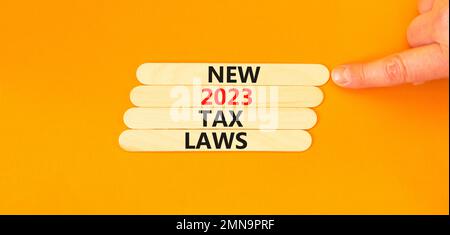 New 2023 tax laws symbol. Concept words New 2023 tax laws on wooden stick. Businessman hand. Beautiful orange table orange background. Business new 20 Stock Photo