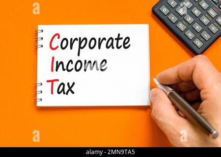 CIT corporate income tax symbol. Concept words CIT corporate income tax on white note on a beautiful orange background. Businessman hand. Business and Stock Photo