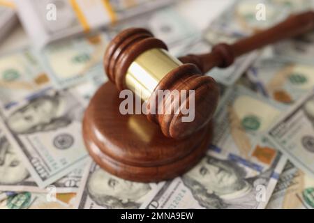 Wooden judge gavel on many dollar bills close up. Stock Photo