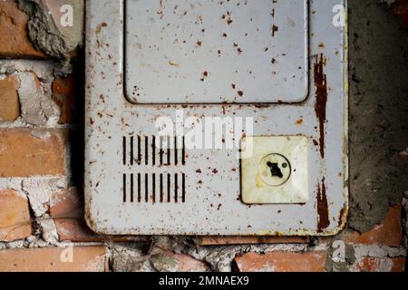 Broken and Damaged Burnt 2 Pin Wall Socket. Blackout concept. Ukraine war. Iron electricity shield on orange old brick wall. Out of focus. Stock Photo