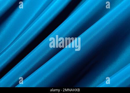 The texture of a smooth elegant fabric of silk, satin blue with folds and waves. Stylish material with wrinkle and bumps Stock Photo