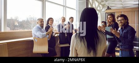 Successful people office workers applaud female employee of company stands with back to camera Stock Photo