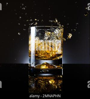 Splash in glass of whiskey on a black background Stock Photo