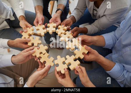 Business team holding and connecting parts of jigsaw puzzle to show concept of teamwork Stock Photo