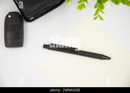 Businessman concept. flat lay black pen on white page next to black wallet and car keys. Stock Photo