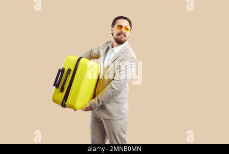 Businessman with yellow travel suitcase goes on business trip or long-awaited vacation. Stock Photo