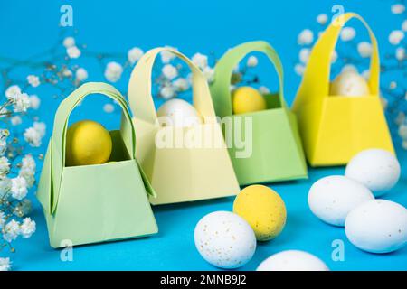 Origami paper baskets and painted quail eggs on a blue background, happy Easter Stock Photo
