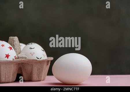 One white and beautifully painted Easter eggs on pink and dark background. Copy space. Happy Easter. Card with copy space for text. Stock Photo