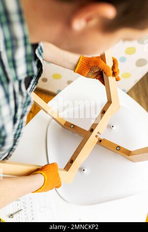 Self-assembly furniture concept. The young man himself assembling chairs Stock Photo